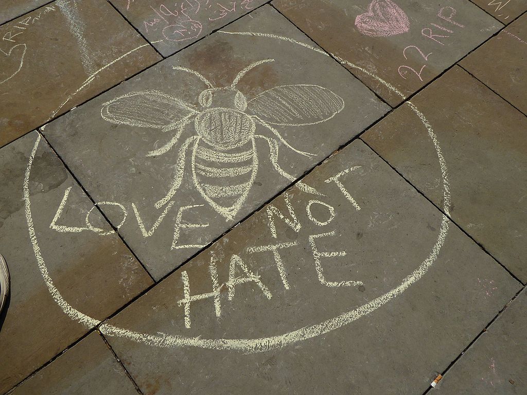 Chalk drawing on pavement depicting a bee (as a symbol of Manchester) and the words LOVE NOT HATE