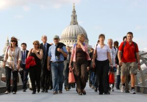 Picture of people walking, looking weary, en mass with St Paul's Cathedral in the background.